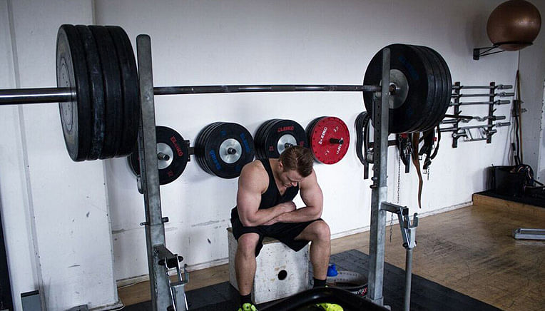 Styrkeløfter holder pause foran squat rack